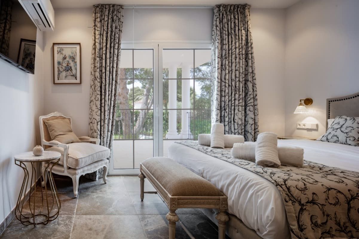 Un dormitorio con dos camas, un banco, una silla y un televisor.