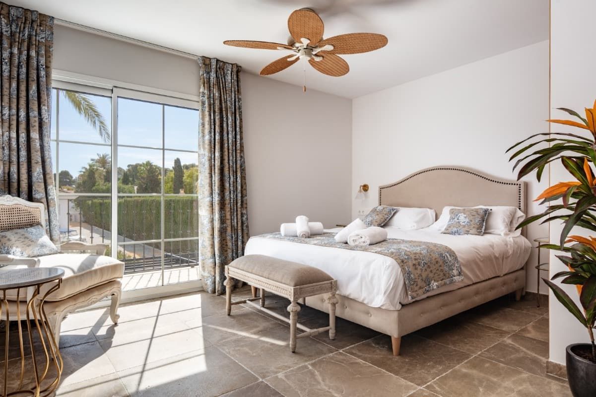 Un dormitorio con una cama king size y un ventilador de techo.