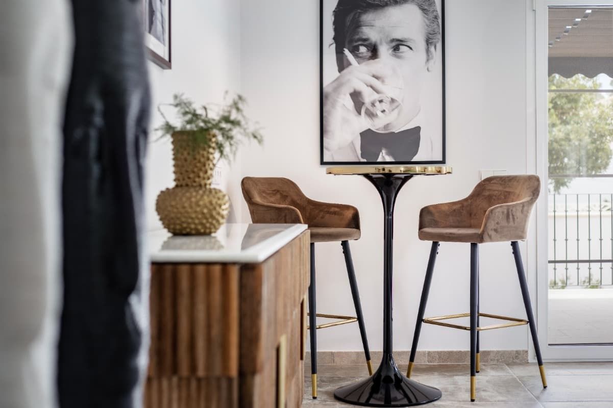 Una habitación con dos taburetes de bar y una mesa con una imagen de un hombre en la pared.