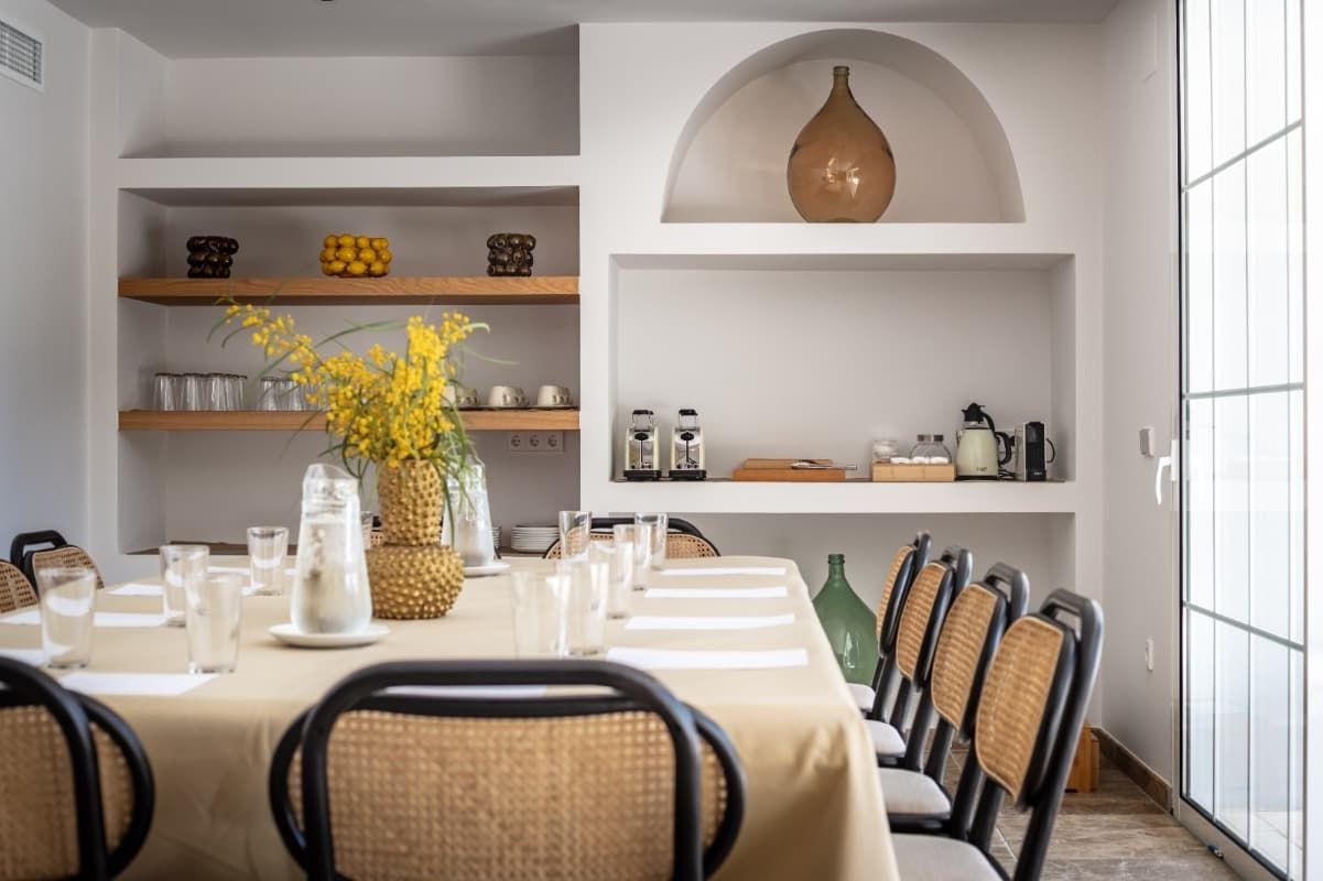 Una mesa larga con sillas y un jarrón con flores sobre ella en una habitación.