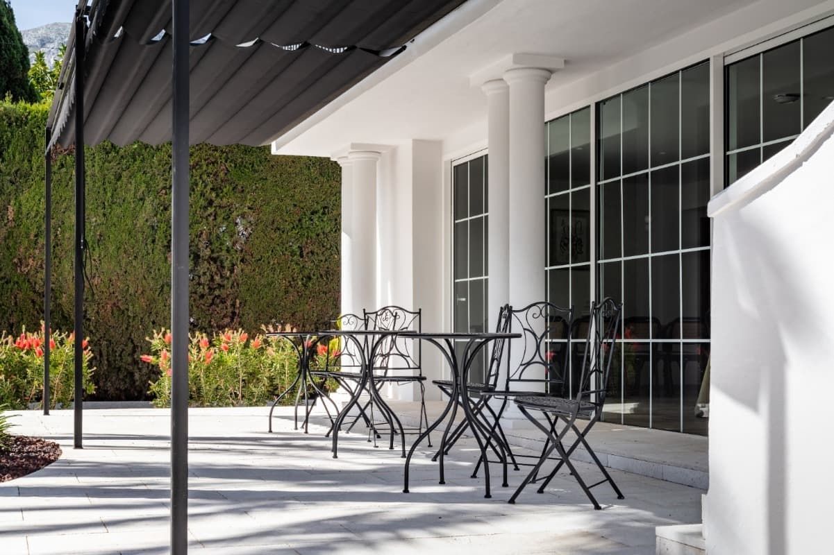 Un patio con mesas y sillas bajo un dosel.