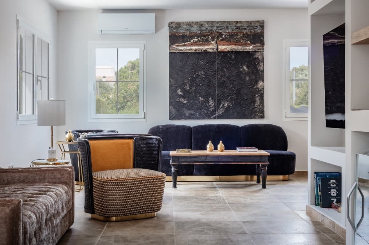 Una sala de estar con sofá, silla, mesa de café y televisión.