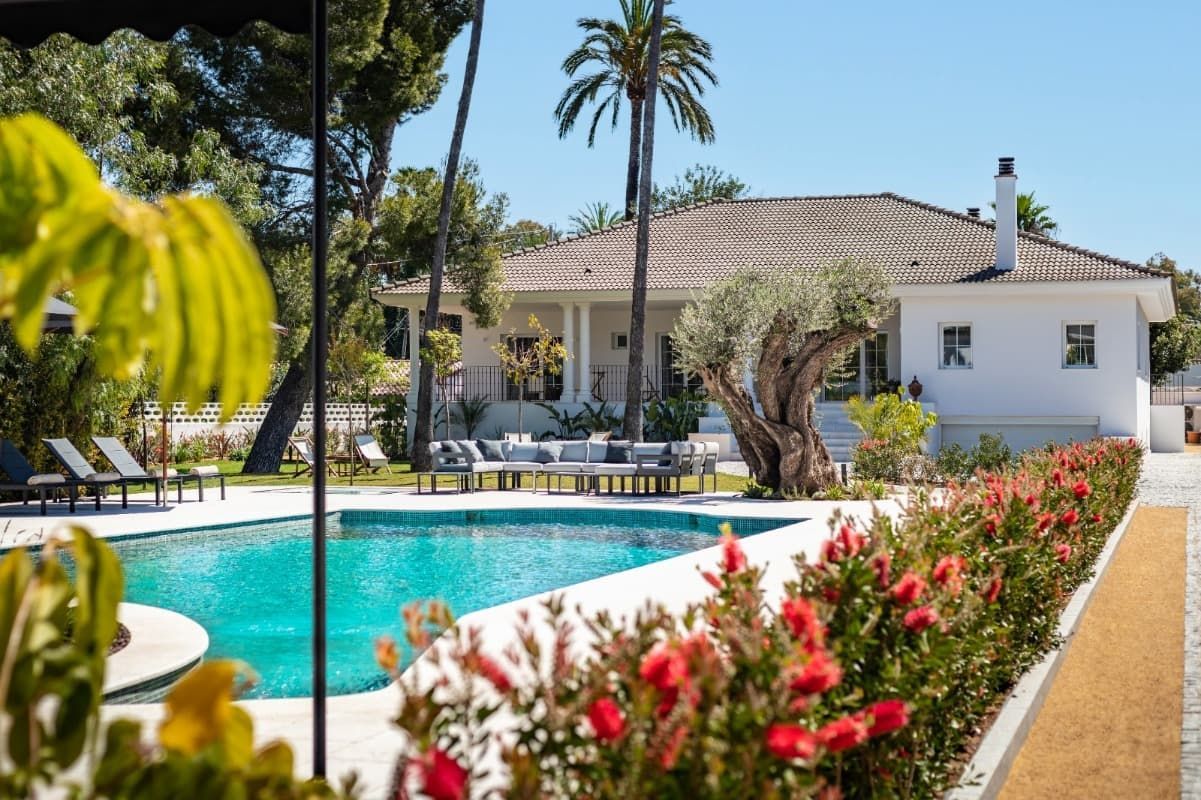 Una gran casa blanca con una piscina delante de ella.