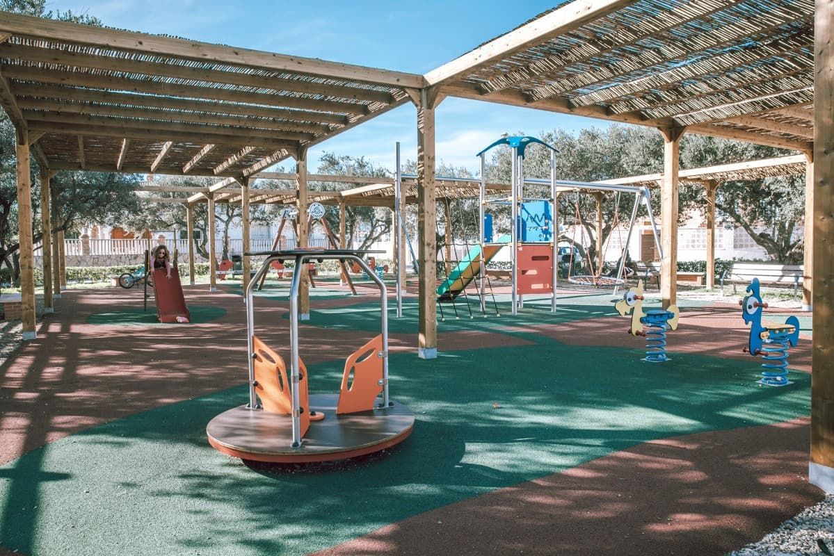 Un parque infantil con un tiovivo y columpios bajo un dosel.
