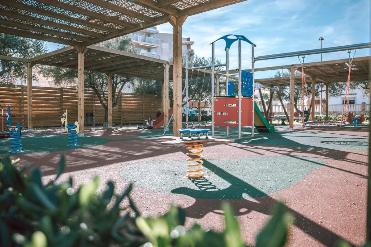 Un patio de juegos con columpios y un tobogán en un parque.