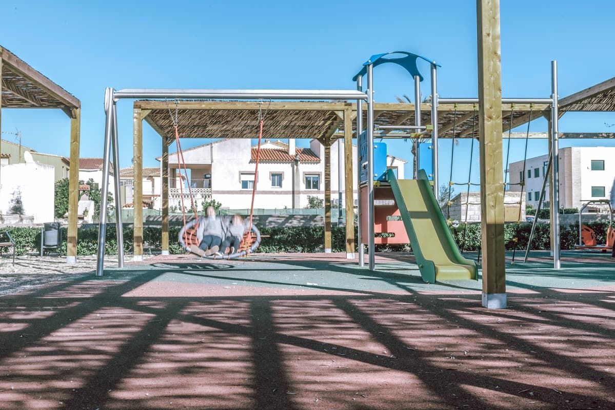Un patio de juegos con tobogán y columpios en un parque.