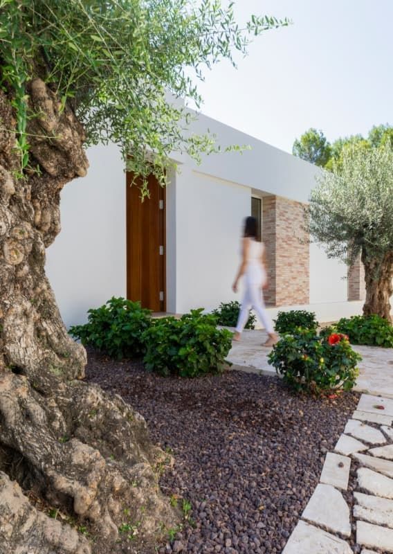 Una mujer camina frente a una casa blanca.