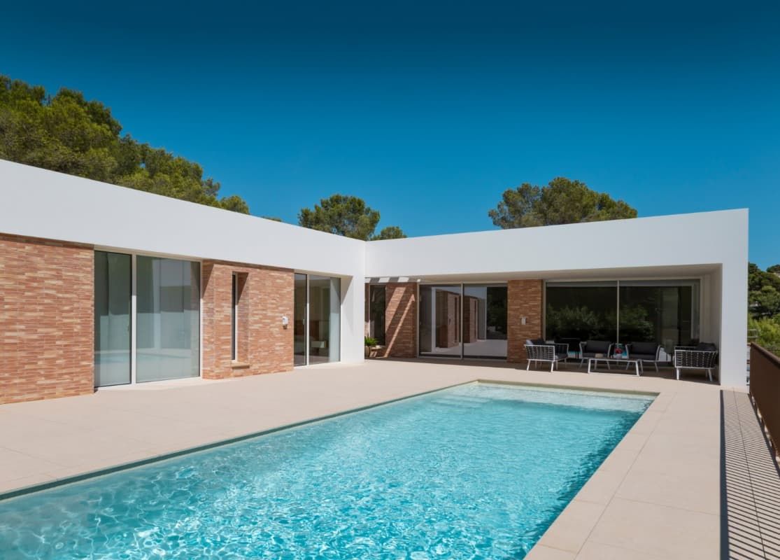 Una casa moderna con una gran piscina en frente de ella.