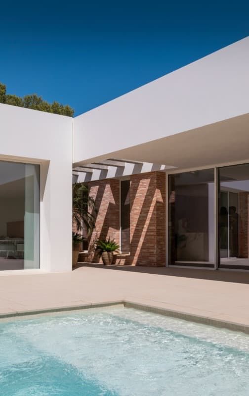 Una casa blanca con una piscina delante de ella.