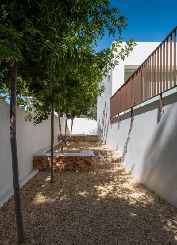 Un edificio blanco con una valla y árboles delante.