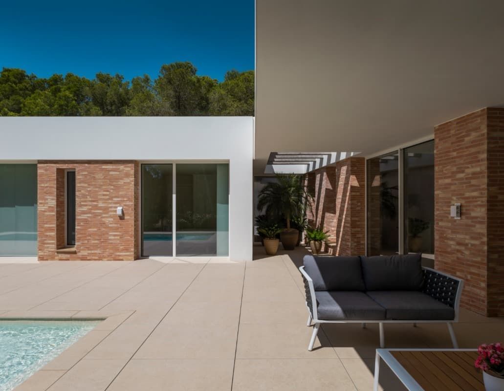 Un patio con un sofá y una mesa junto a una piscina.