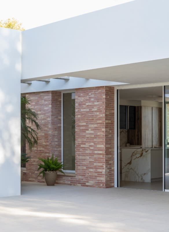 Un edificio de ladrillo con una puerta corrediza de vidrio y una planta en maceta frente a él.