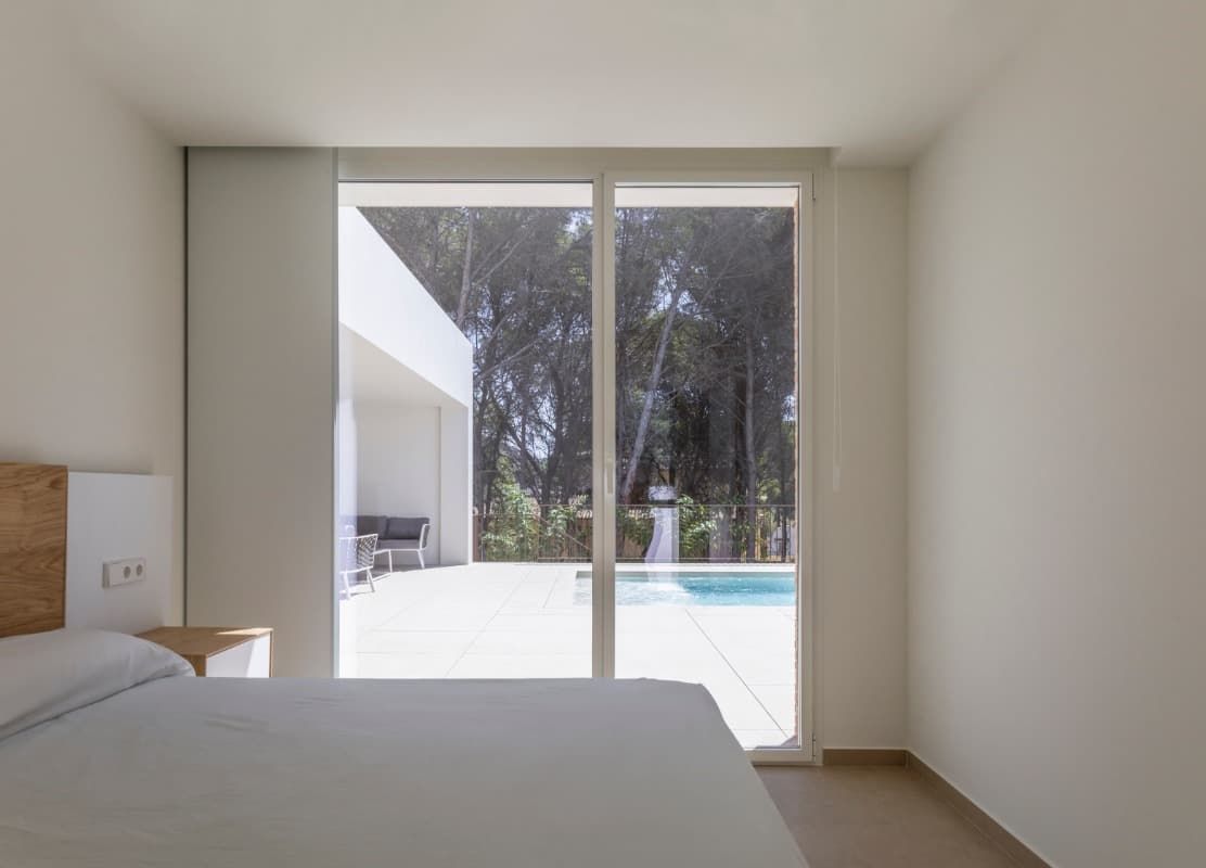 Un dormitorio con una cama y una puerta corrediza de vidrio que conduce a una piscina.