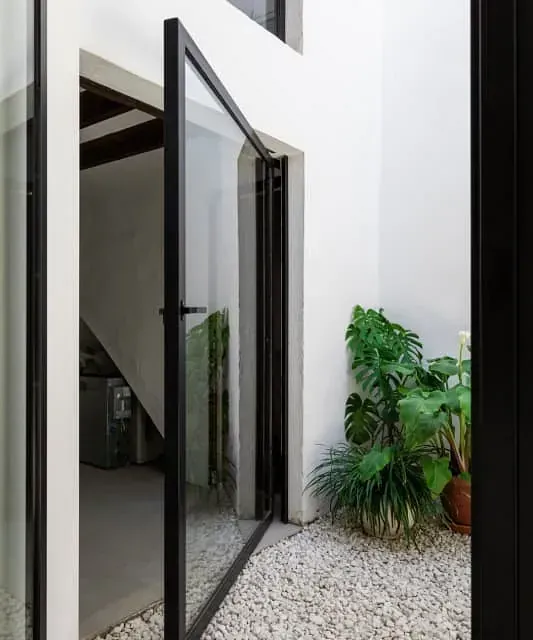 Una puerta de cristal se abre a un patio con plantas en macetas.
