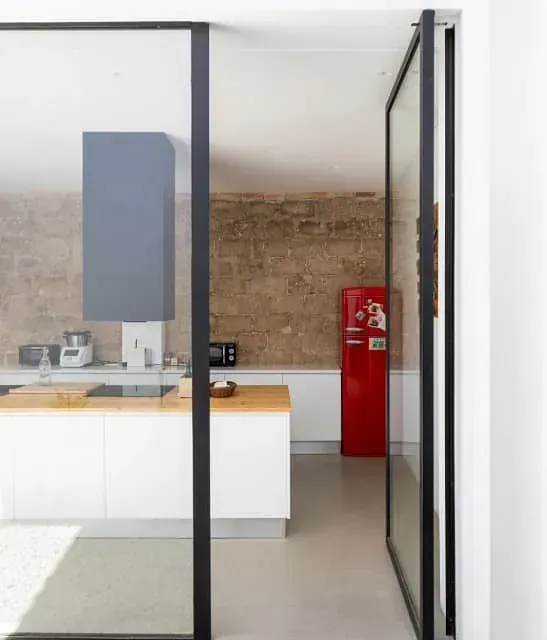 Una cocina con gabinetes blancos y un refrigerador rojo.