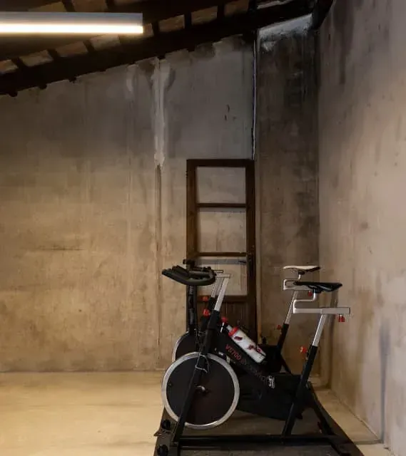 Dos bicicletas estáticas están aparcadas en una habitación una al lado de la otra.