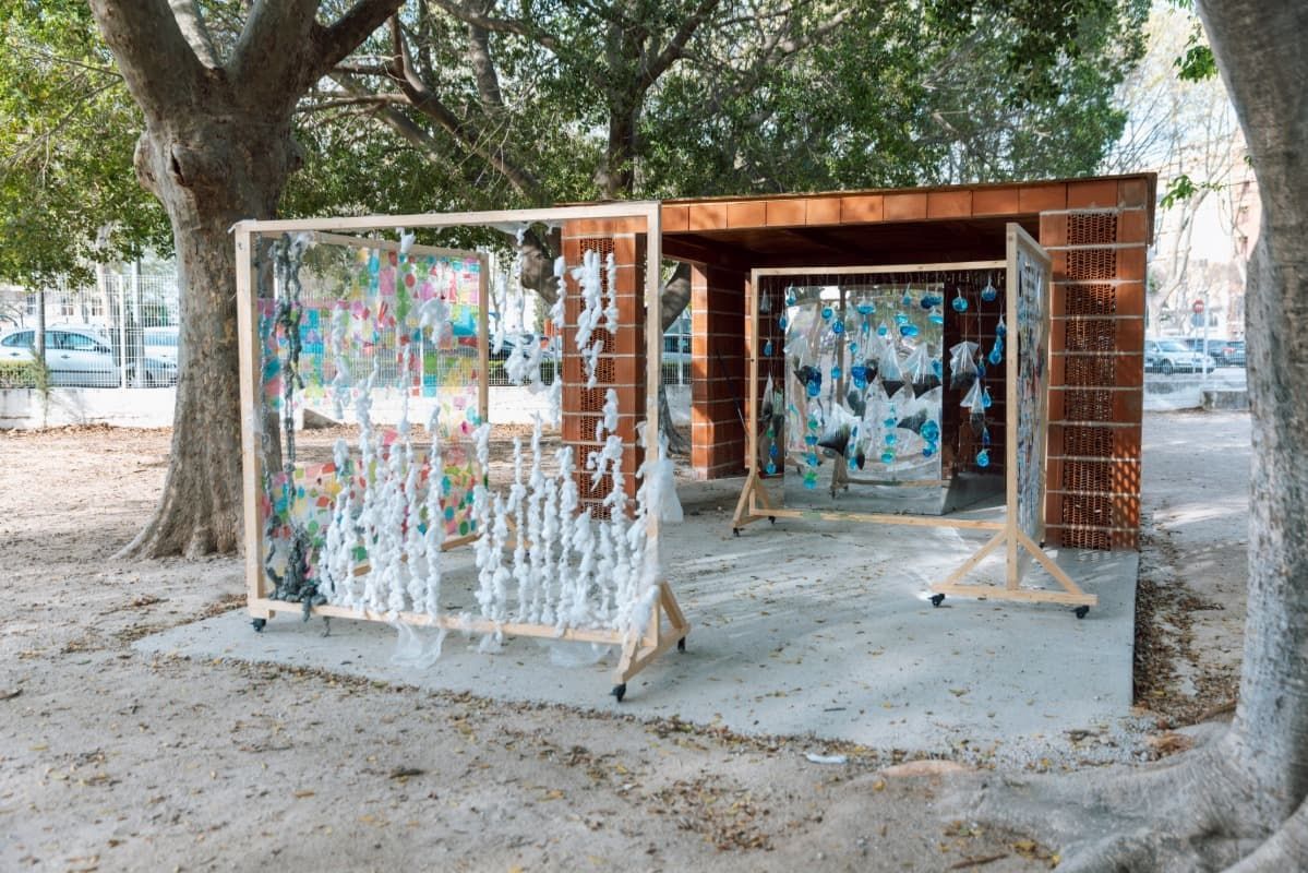 Un edificio de ladrillo está rodeado de árboles y una exposición de pinturas en un parque.