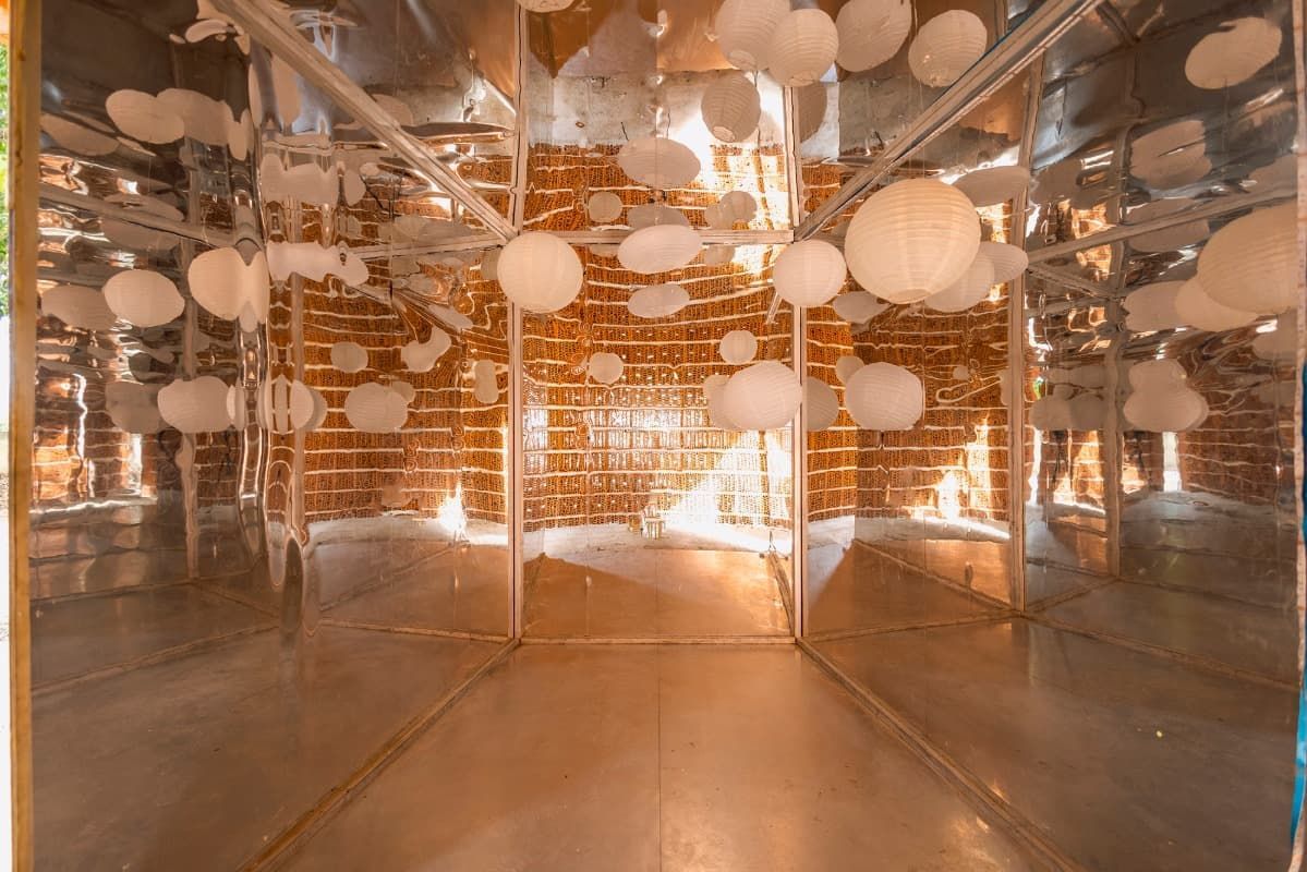 Una habitación con muchos espejos y globos colgando del techo.