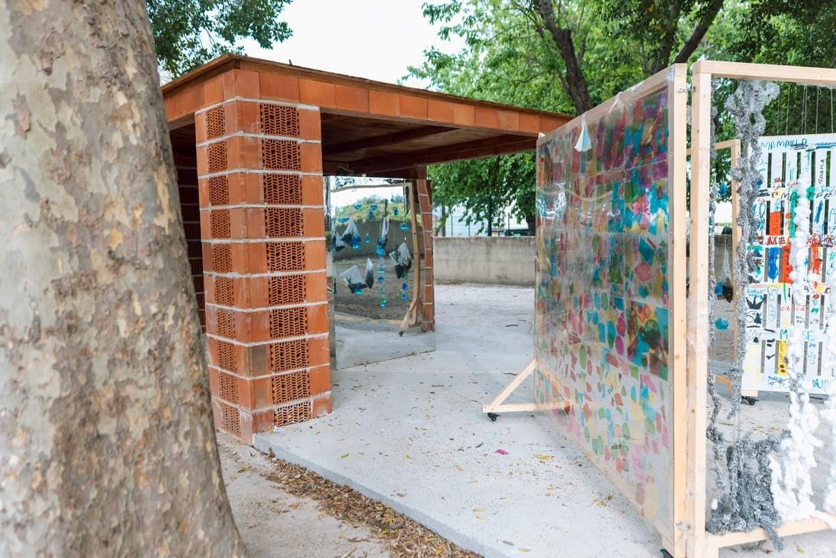 Un edificio de ladrillo con una valla y un árbol al fondo.