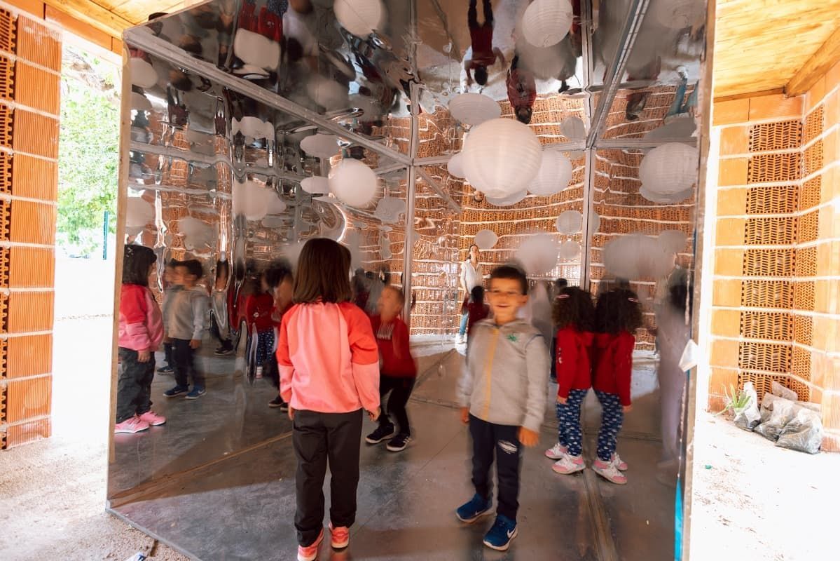 Un grupo de niños está de pie en una habitación con globos colgando del techo.