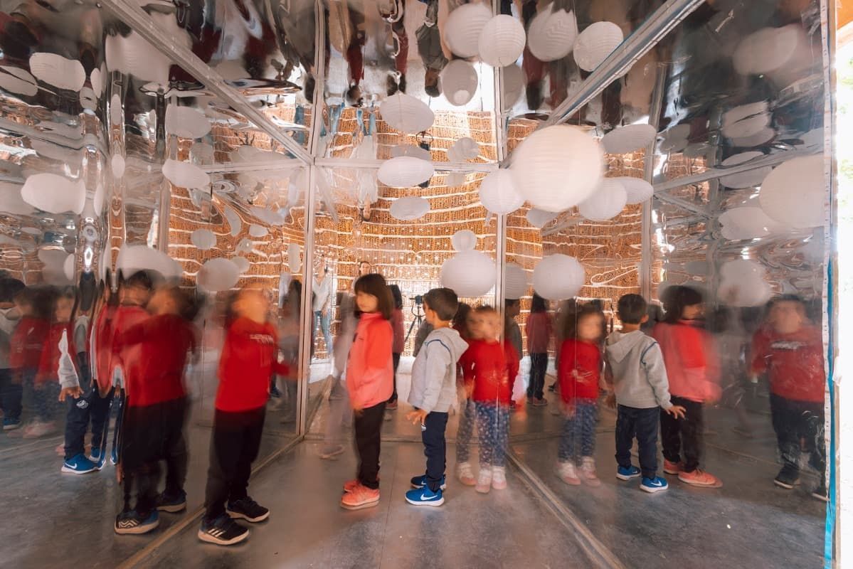 Un grupo de niños está de pie en una habitación con globos colgando del techo.