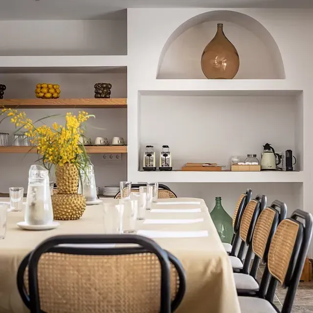 Un comedor con una mesa y sillas y un jarrón de flores encima.