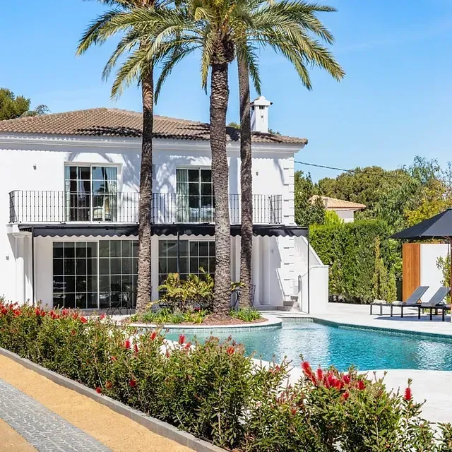 Una gran casa blanca con una piscina delante de ella.