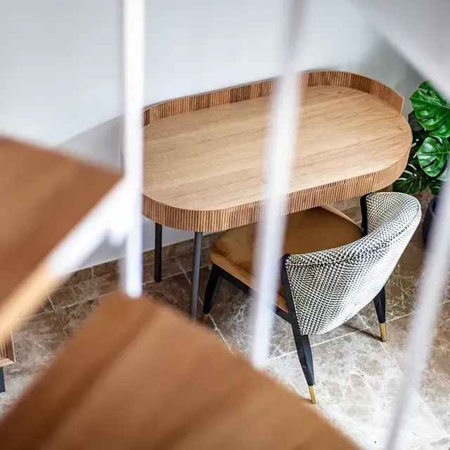 Una mesa y una silla de madera en una habitación con escaleras.