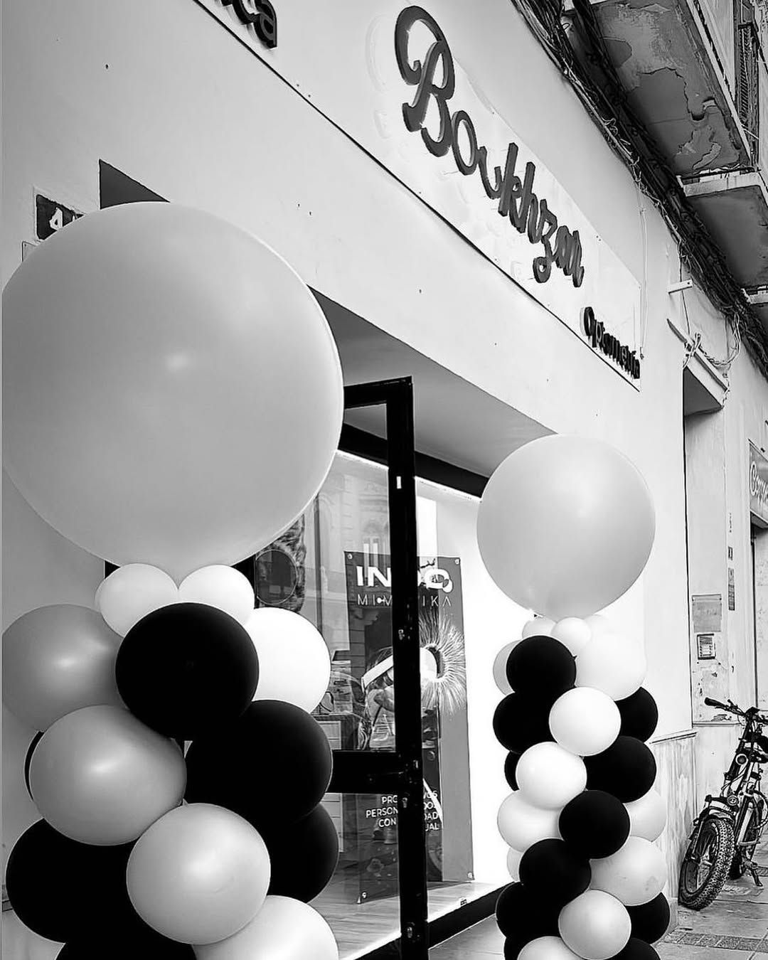 Entrada a una panadería decorada con columnas de globos blancos y negros.