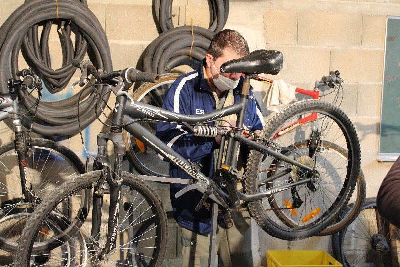 Homme alignant les rayons d'un vélo avec une clé spéciale