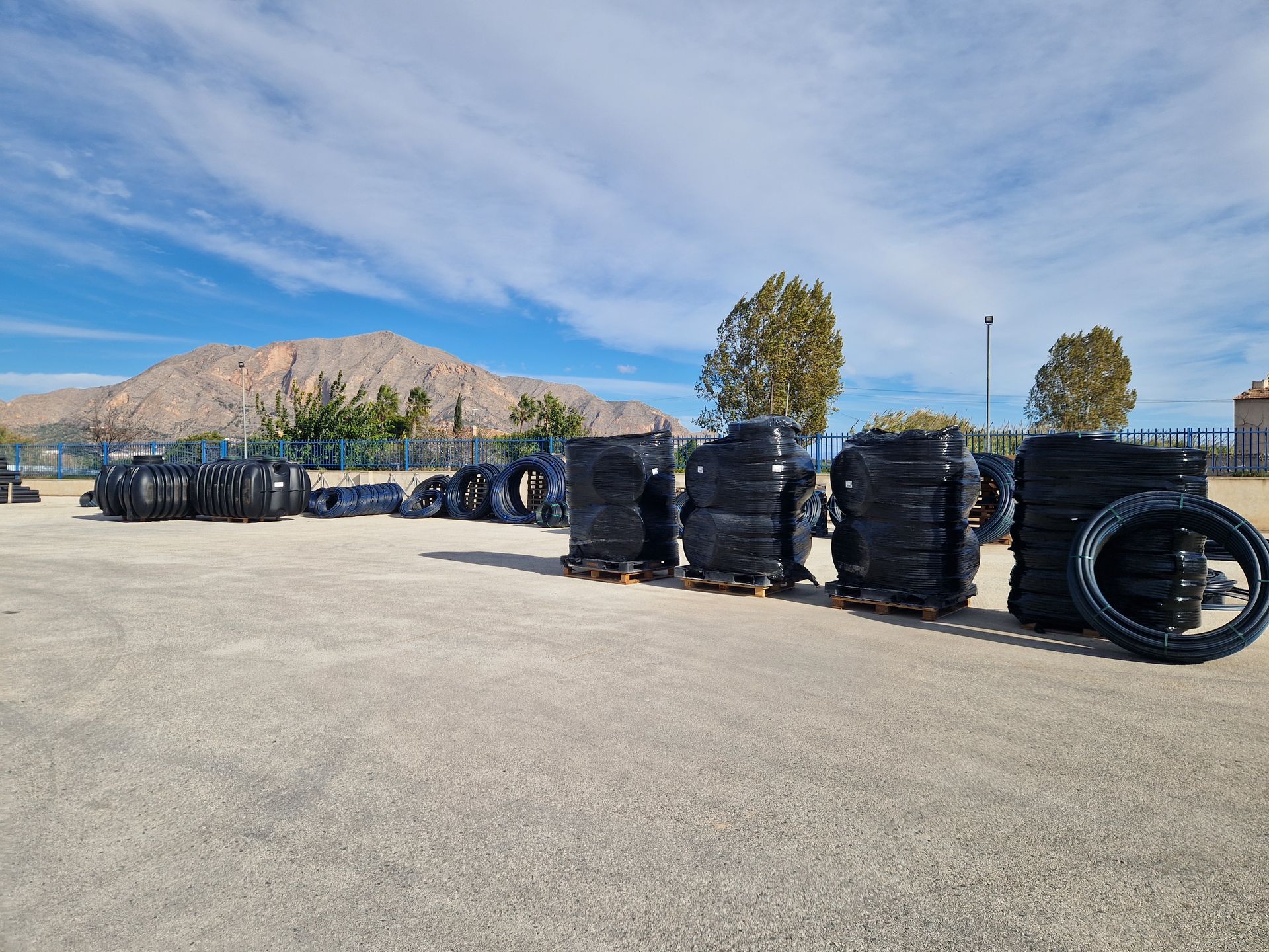 Neumáticos apilados en paletas al aire libre con montañas al fondo bajo un cielo azul.