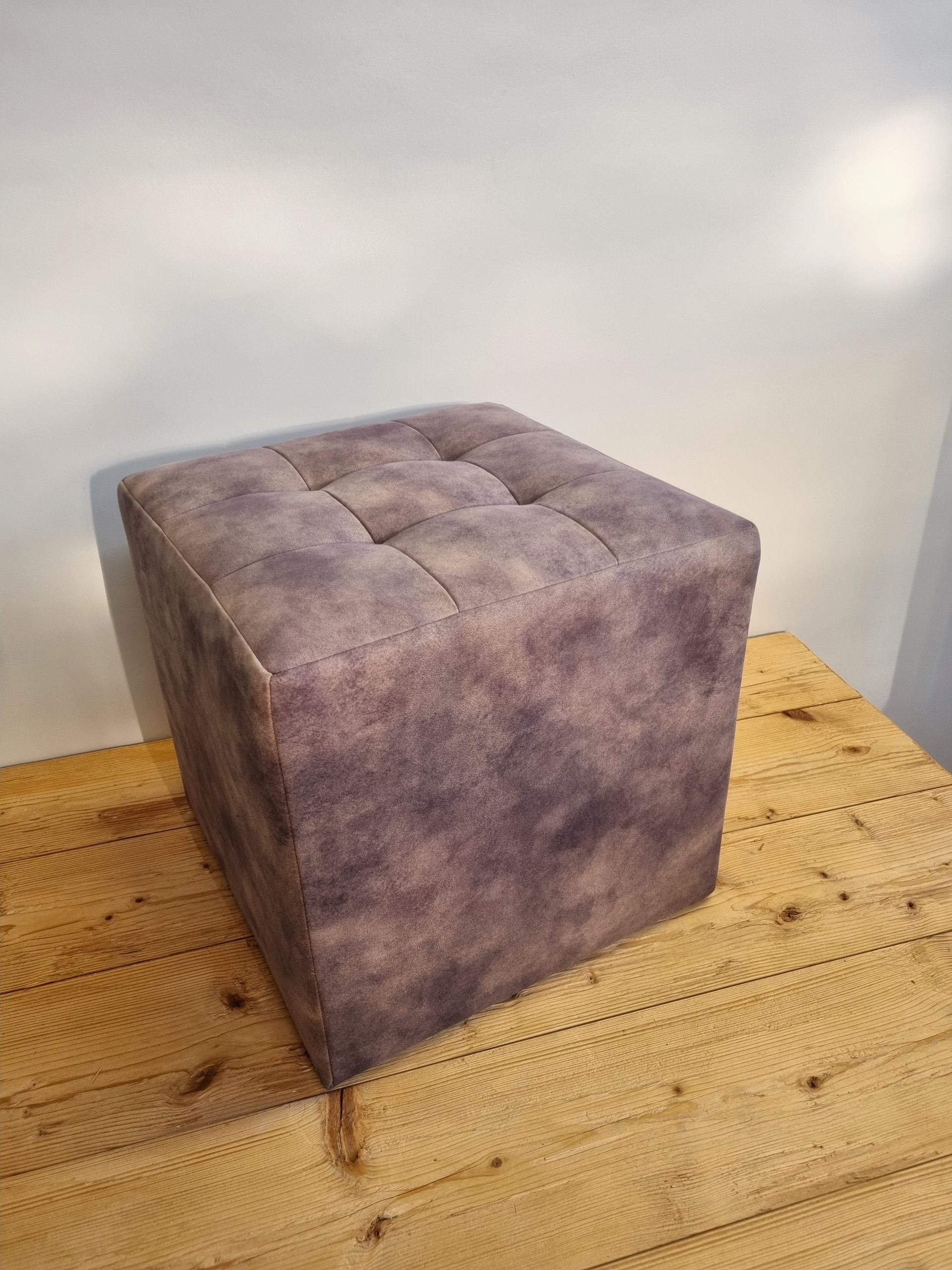 Auf einem Holztisch steht ein lila Ottomane.