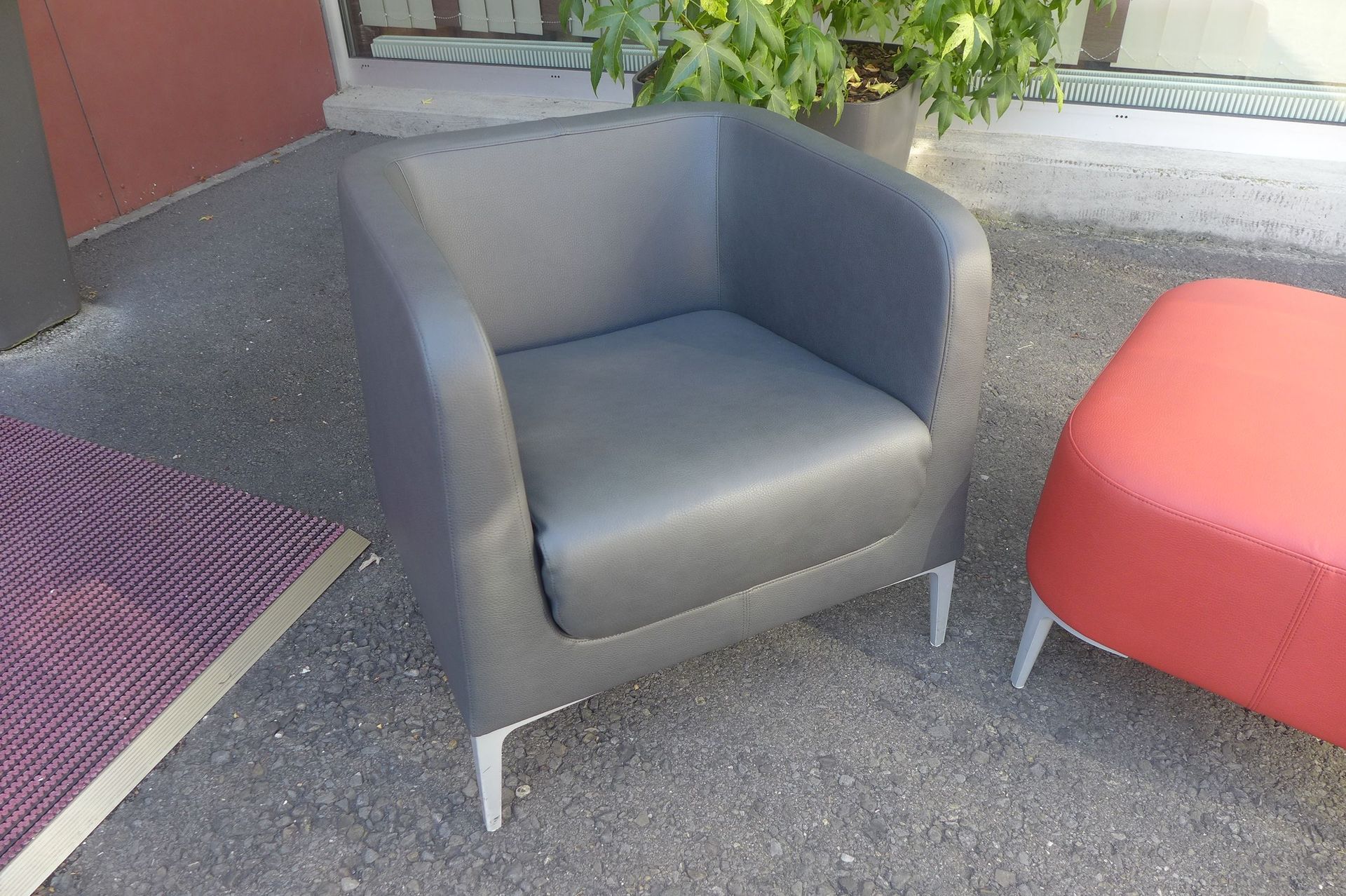 Ein schwarzer Stuhl und ein roter Ottomane stehen auf dem Boden