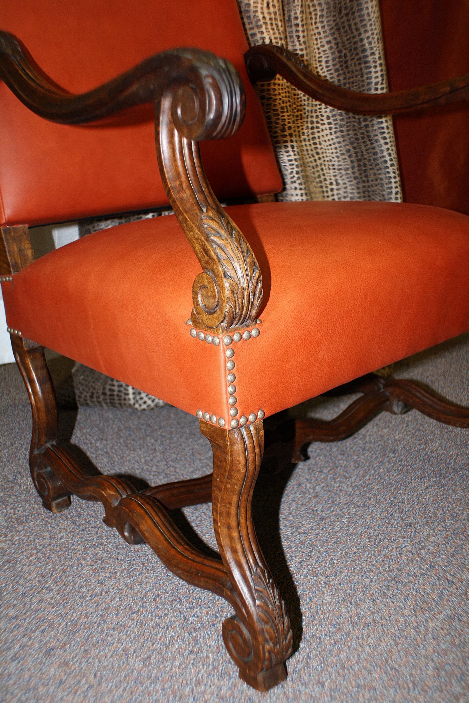 Ein Holzstuhl mit roter Sitzfläche und Armlehnen