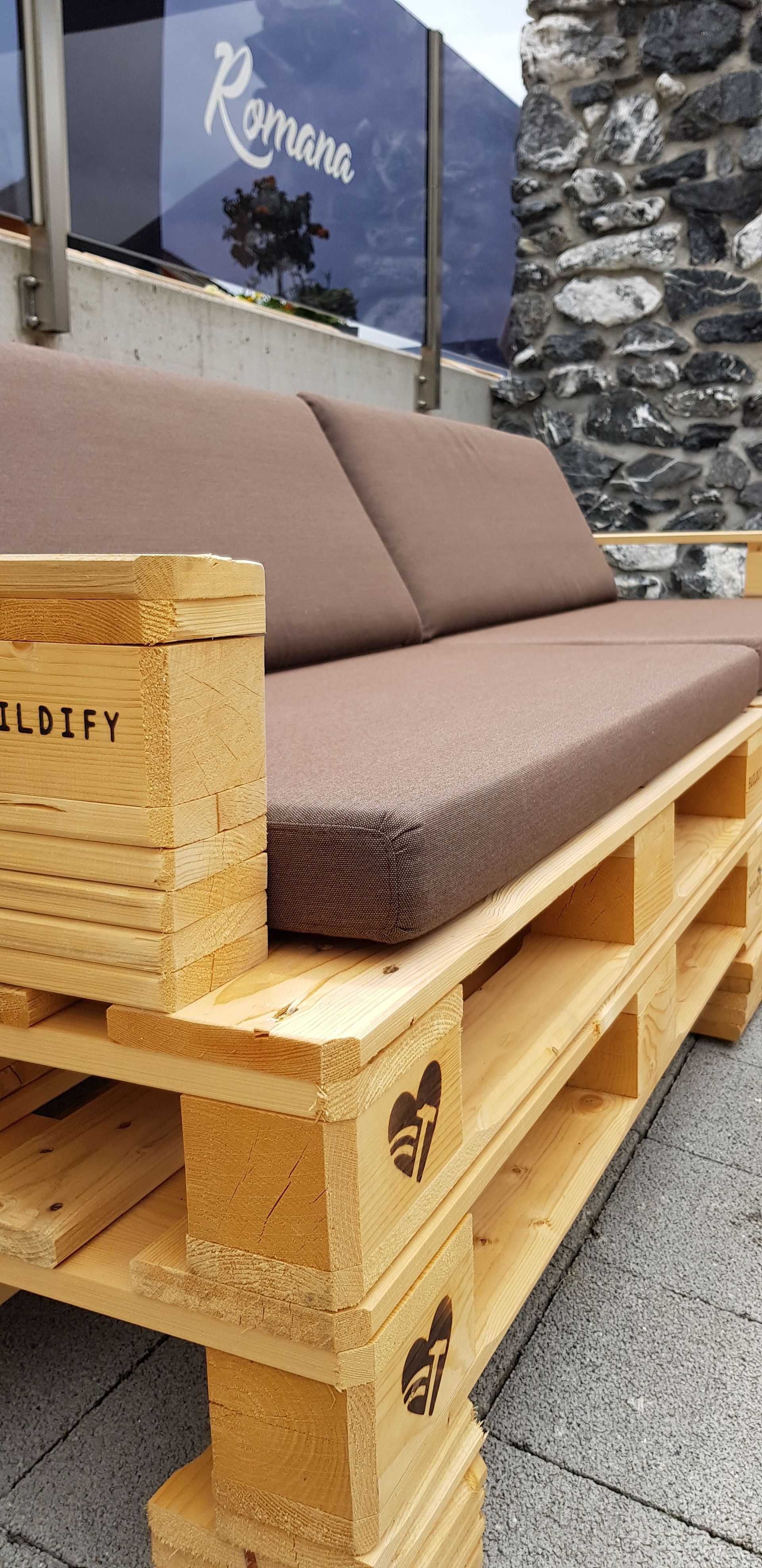 Ein Holzsofa aus Holzpaletten mit einem braunen Kissen.