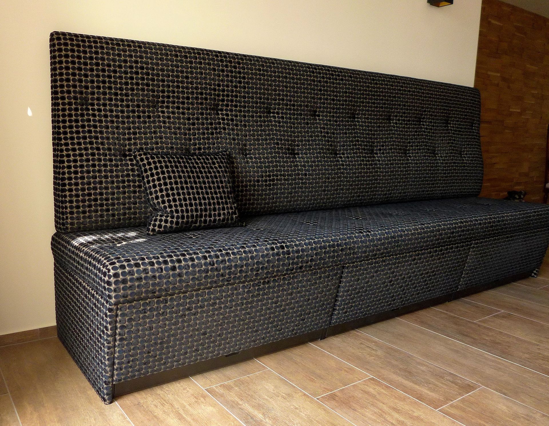 Eine lange schwarze Couch steht auf einem Holzboden