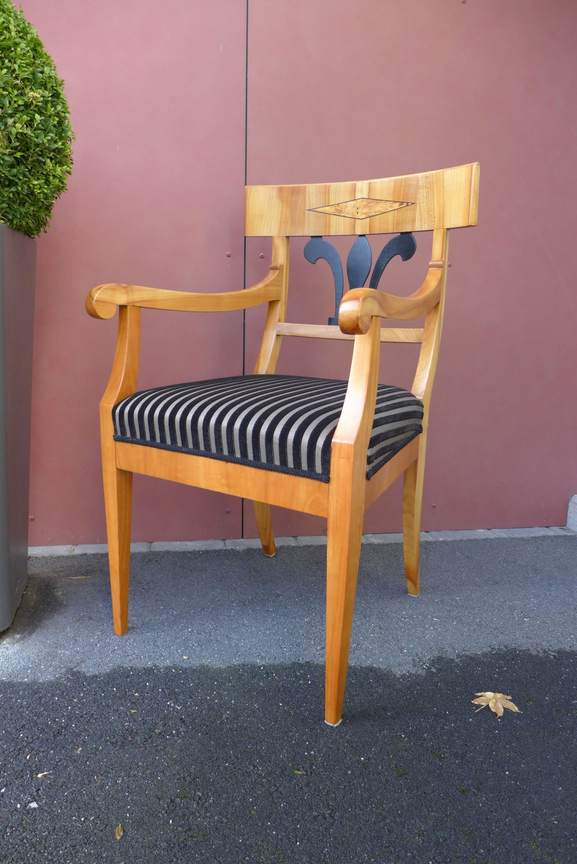 Ein Holzstuhl mit schwarz-weiß gestreifter Sitzfläche