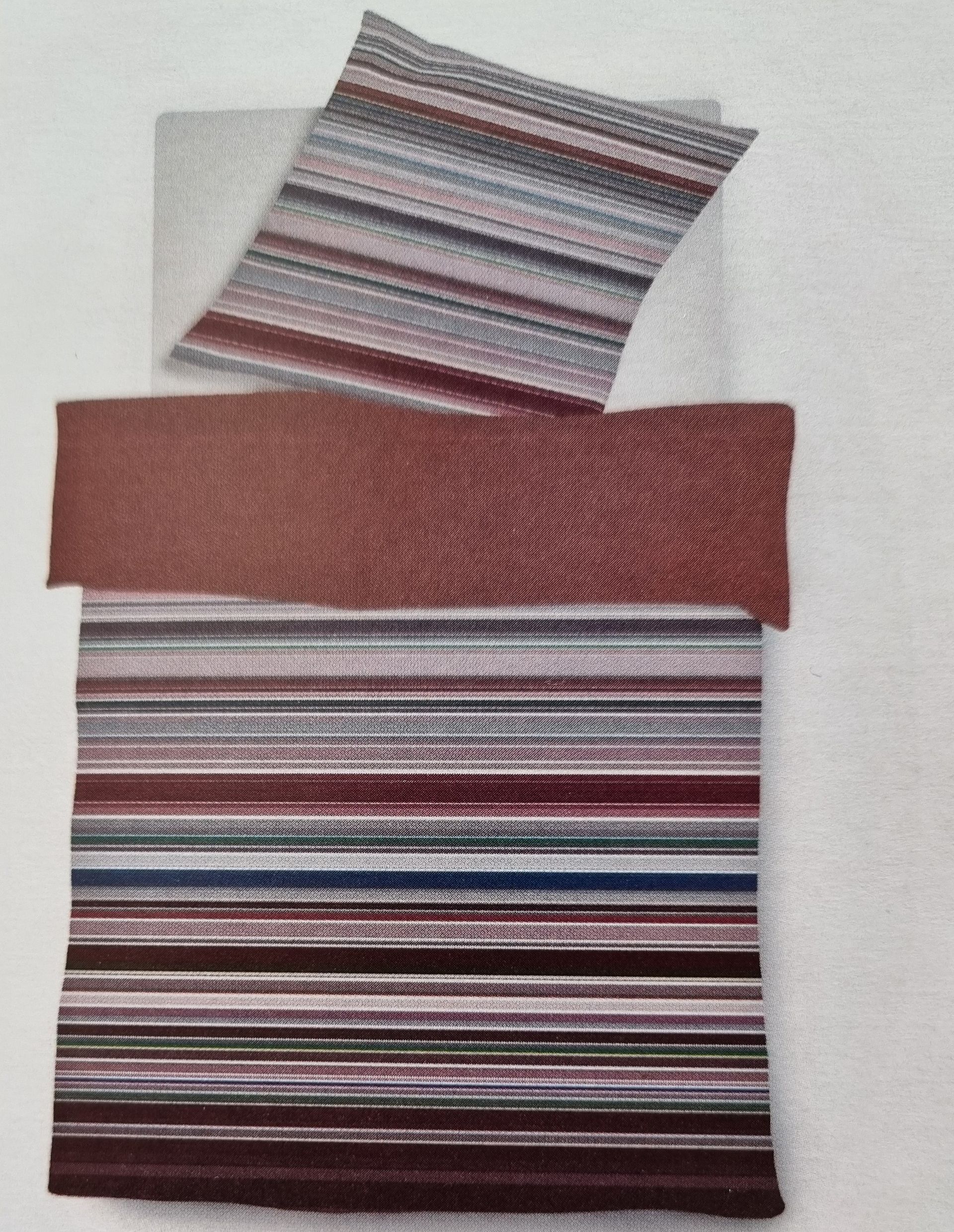 Ein Bett mit einer gestreiften Bettdecke und Kissen darauf