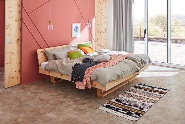 Ein Schlafzimmer mit einem Holzbett und einem Teppich auf dem Boden.