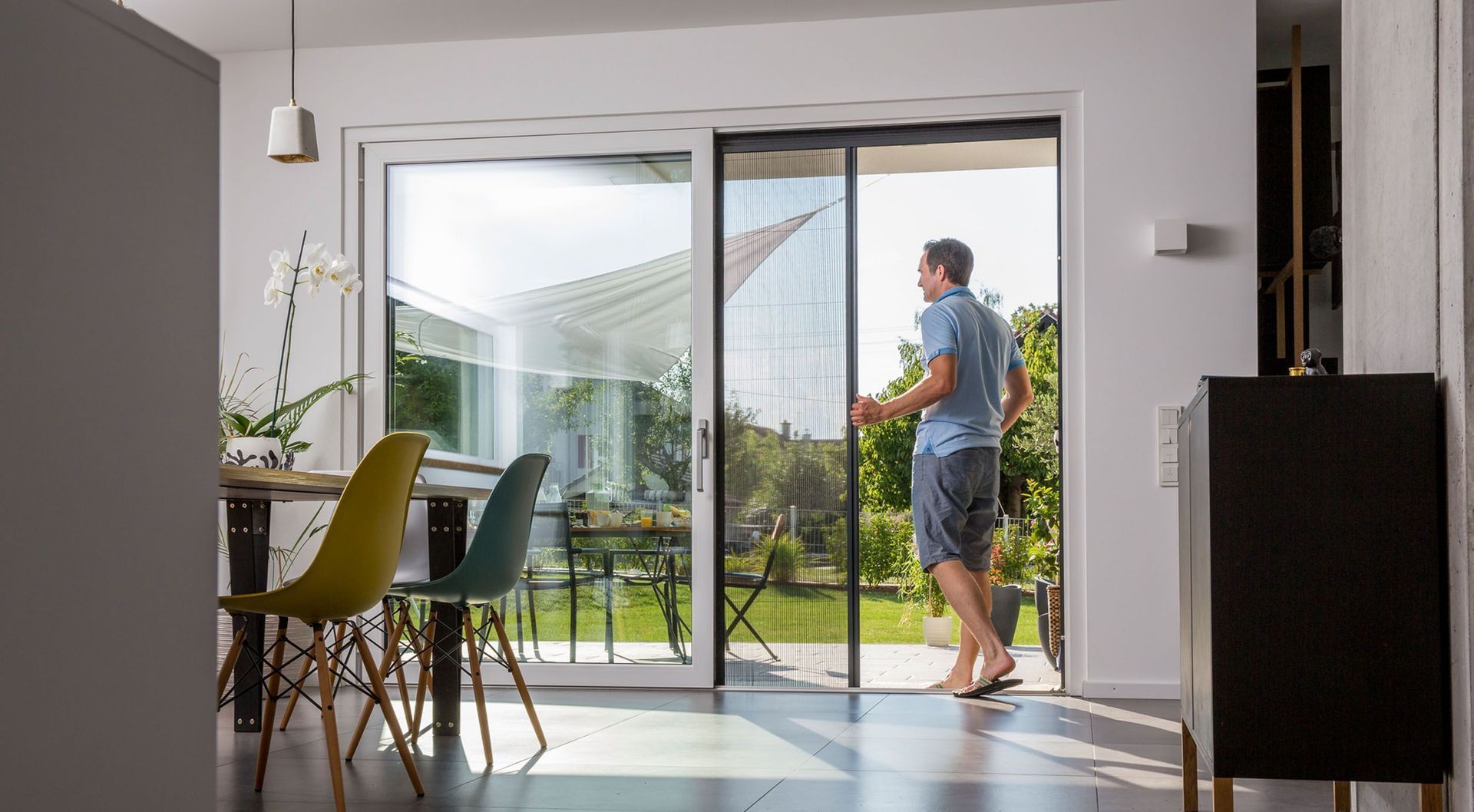 Ein Mann steht in einem Wohnzimmer neben einer Glasschiebetür.