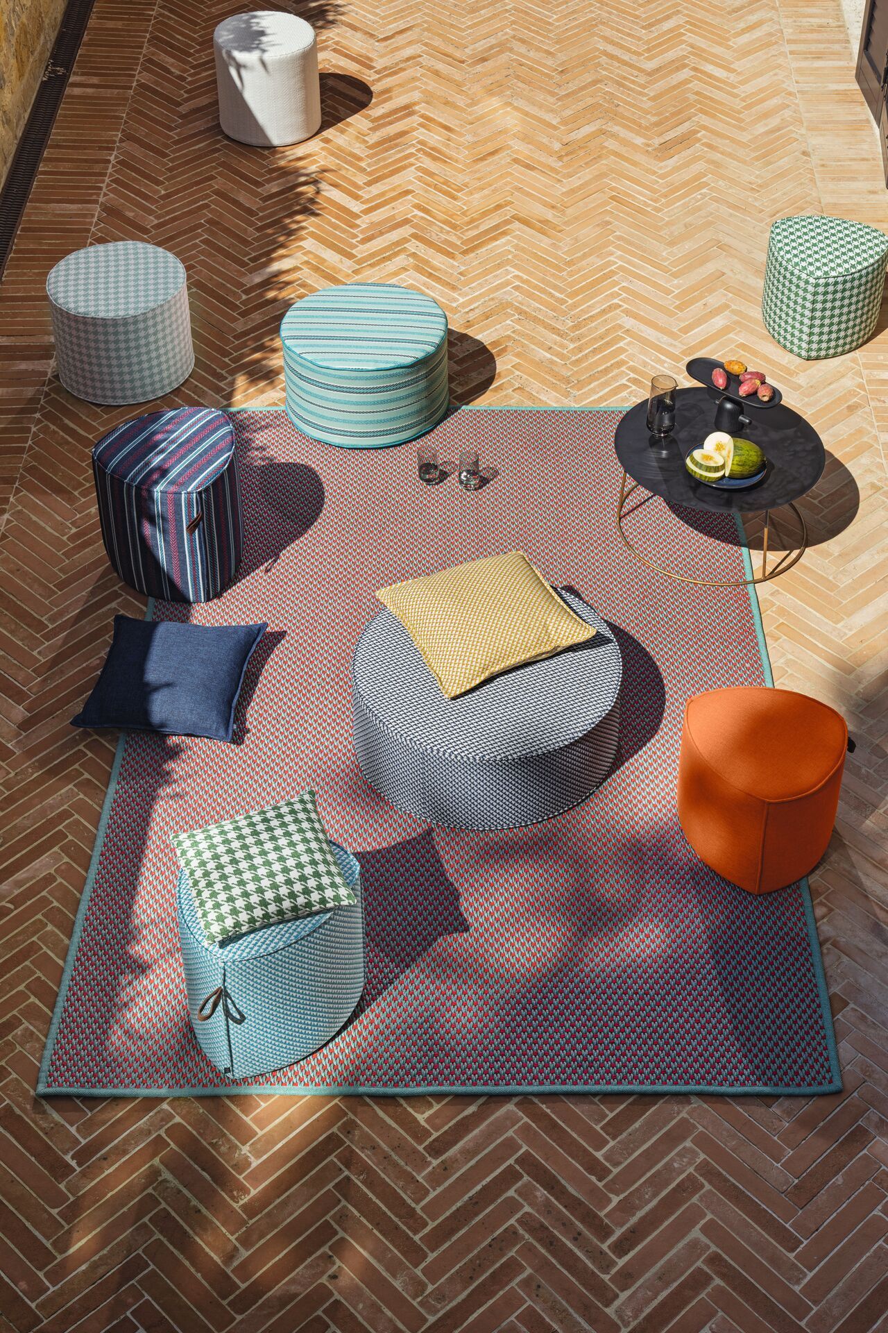 Eine Gruppe von Ottomanen und Kissen liegt auf einem Teppich auf einem Holzboden.