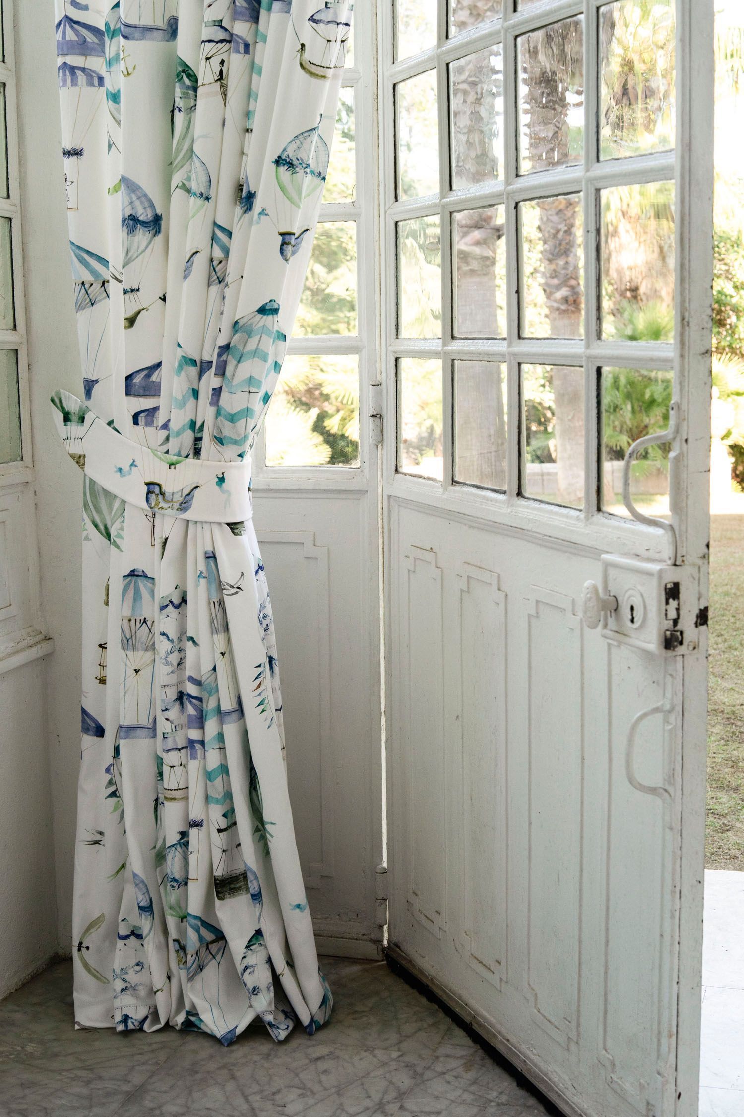 Eine weiße Tür, an der ein blau-weißer Vorhang hängt.