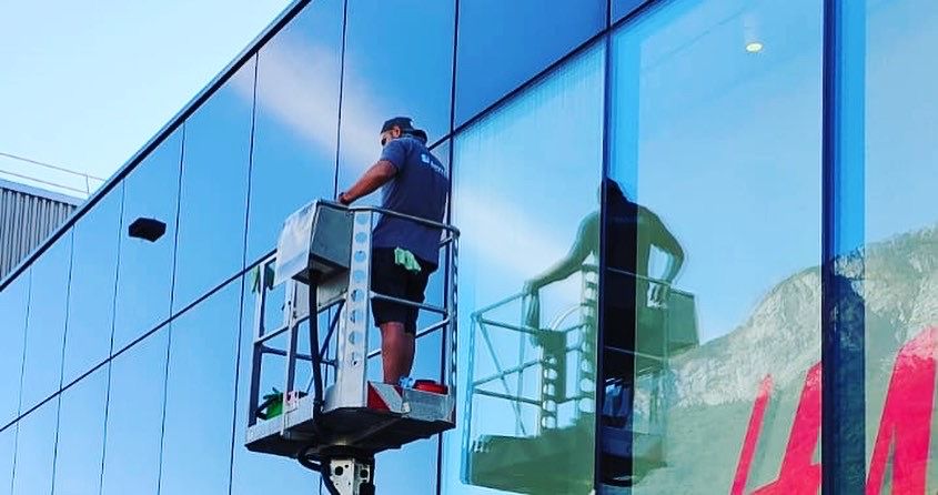 Arbeiter reinigt in einem Aufzug die Glasfassade eines Gebäudes