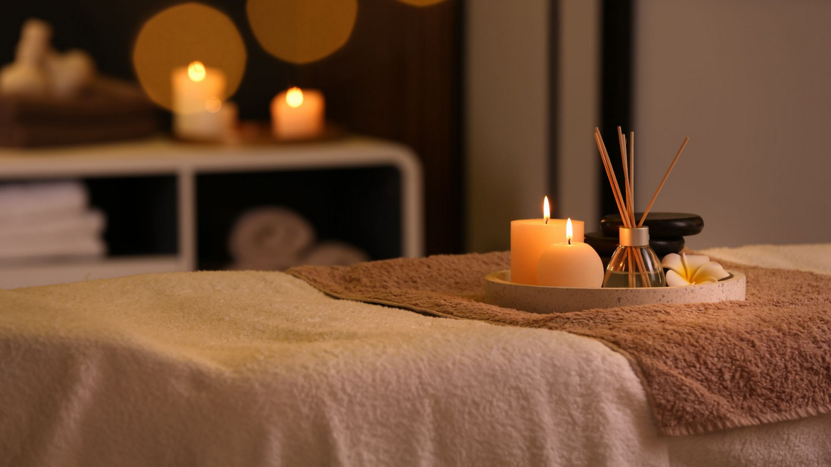Salle de soins Spa avec bougies allumées, diffuseur d'huiles essentielles et serviettes pliées.