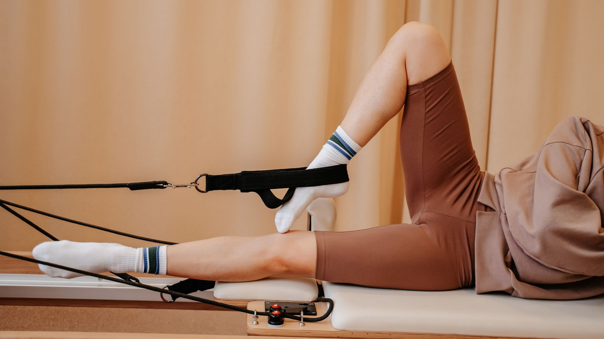 Personne faisant des exercices pour les jambes avec un élastique de résistance, allongée sur une surface rembourrée.