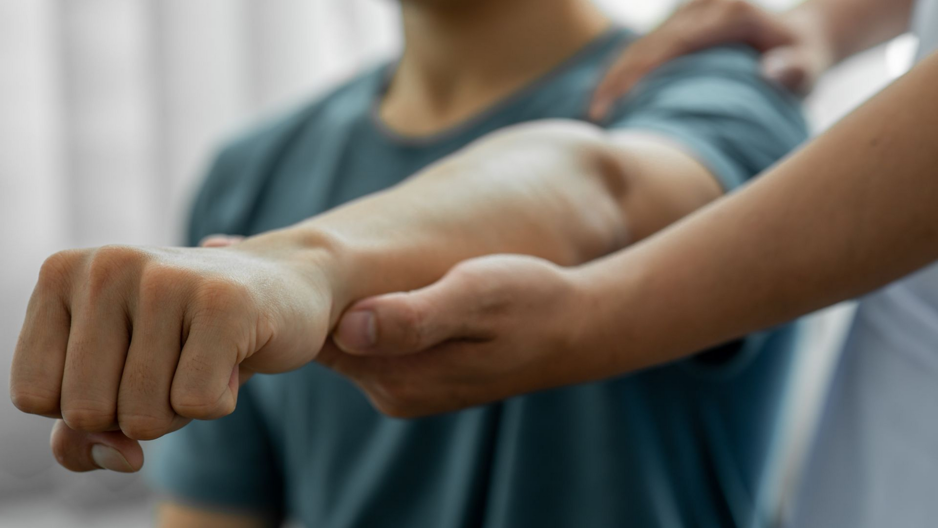 Le bras d'une personne est soutenu par la main d'une autre personne lors d'un exercice de physiothérapie.