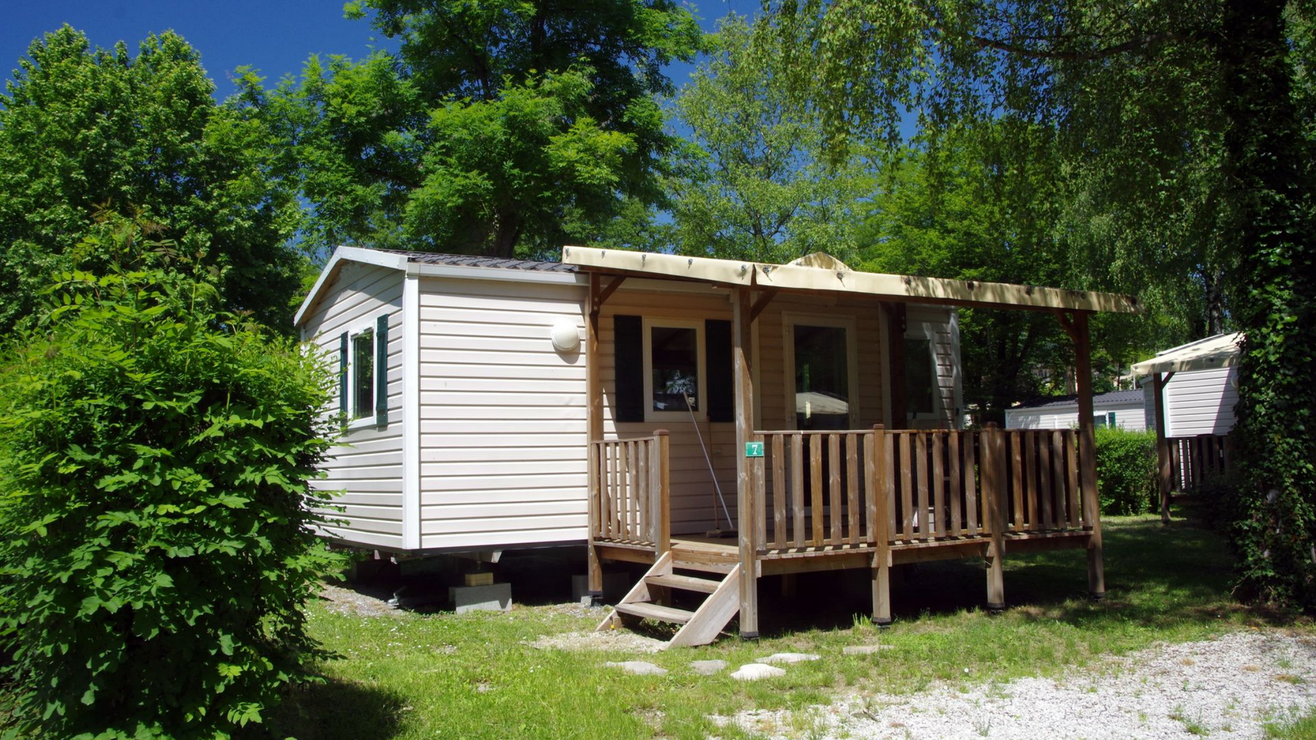 Cabane avec porche et marches en bois, nichée au milieu des arbres et de la verdure.