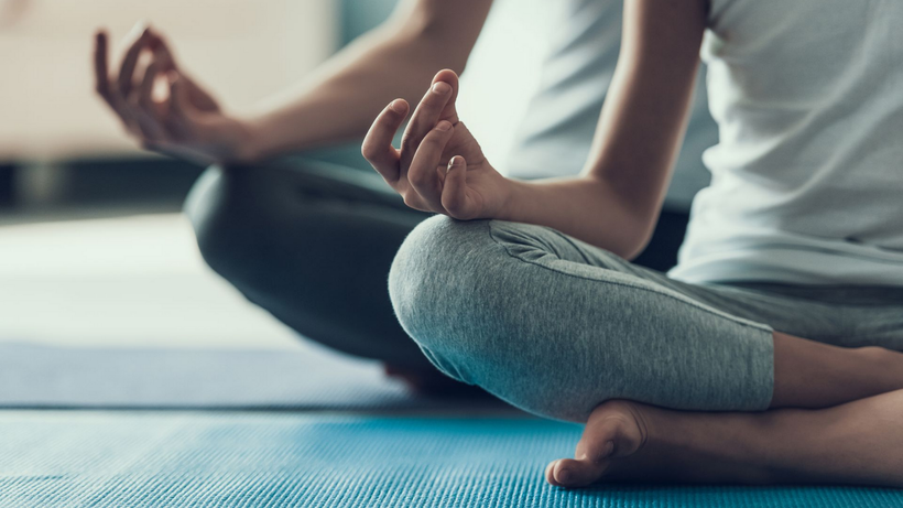 Personne assise en tailleur, les mains dans une position méditative, pratiquant le yoga.