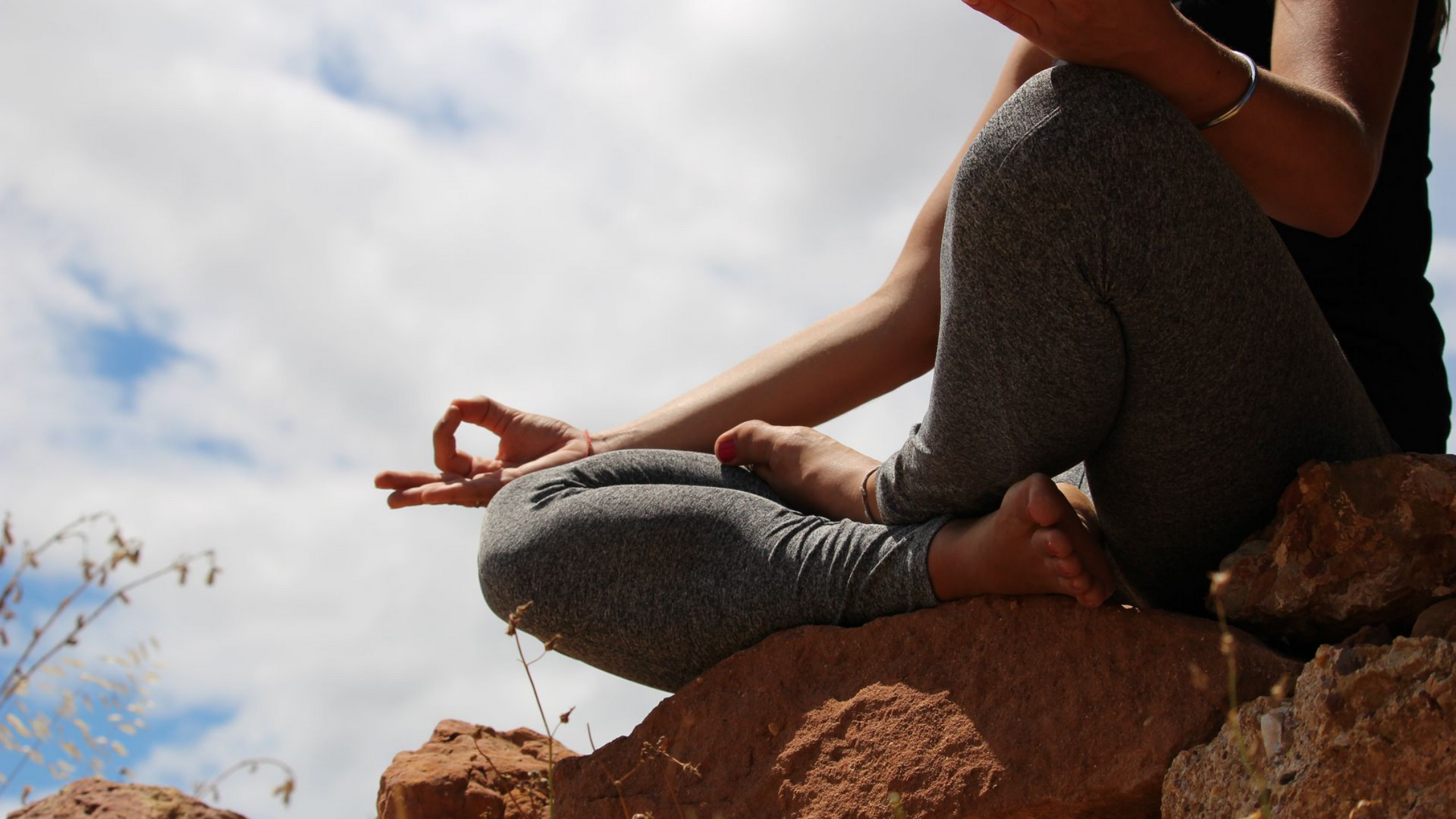 Personne en position du lotus sur des rochers.