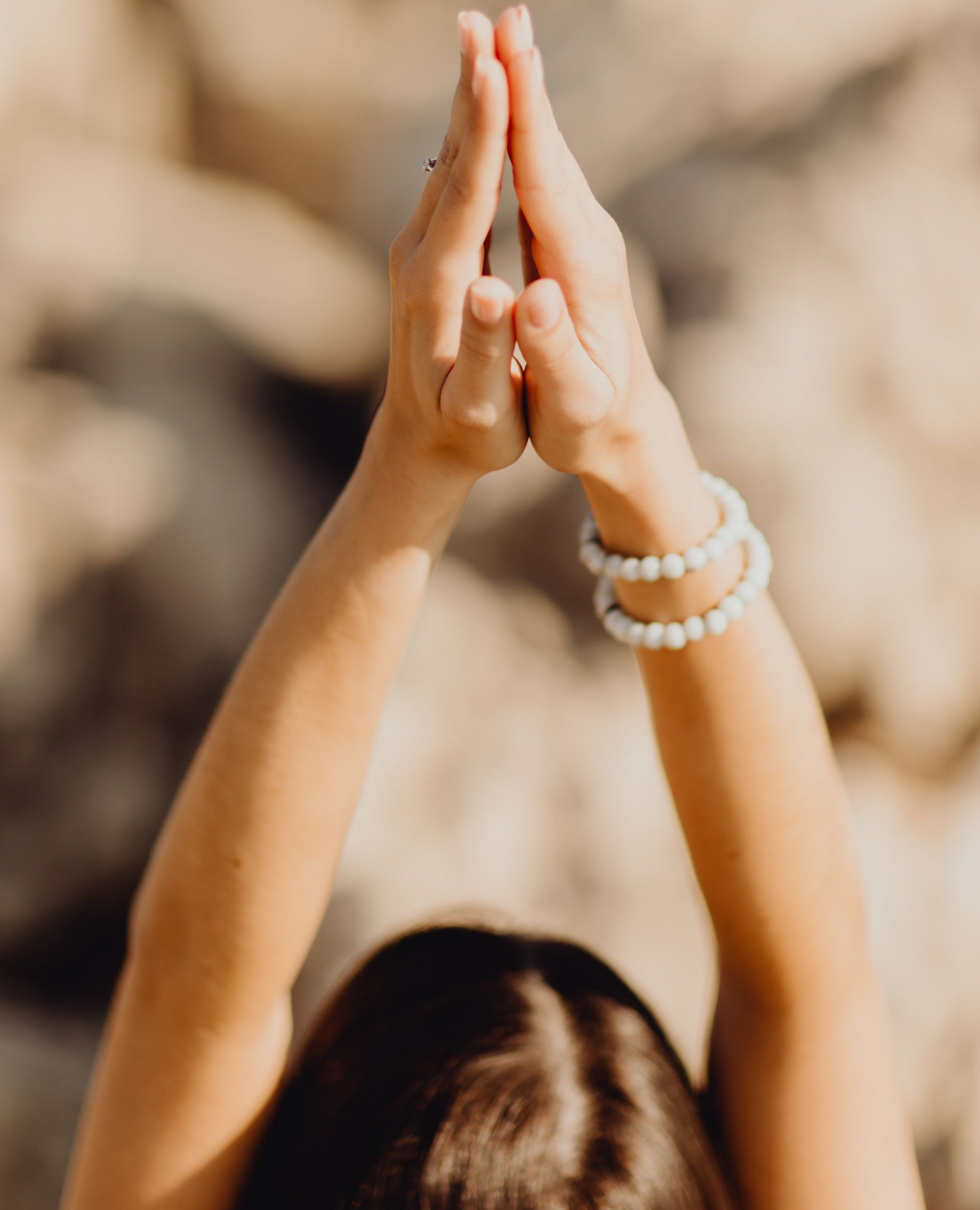 Mains d'une personne levées, paumes jointes en position de relaxation.